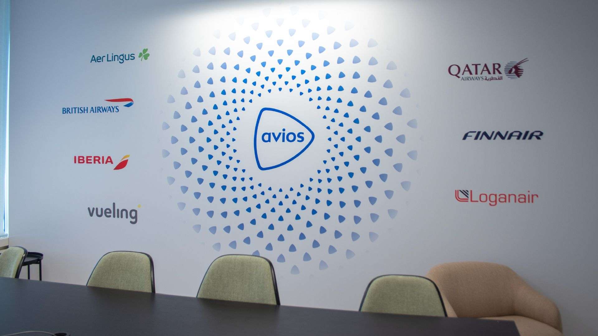 The Avios logo surrounded by 7 airline logos on a wall in an office space