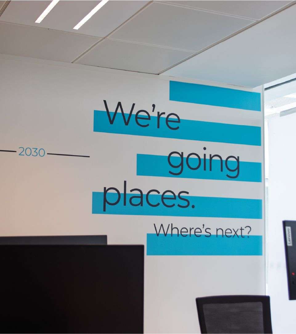 'We're going places. Where next?' on the wall of an office space